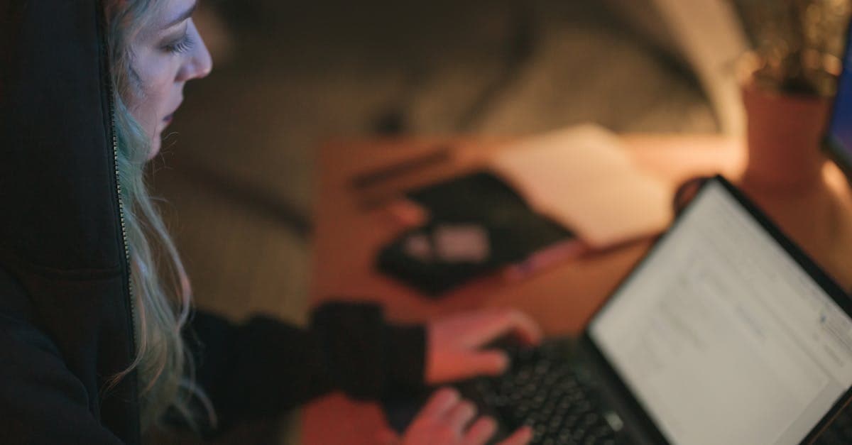 Young woman focused on laptop work at a dimly lit desk, creating a cozy atmosphere.