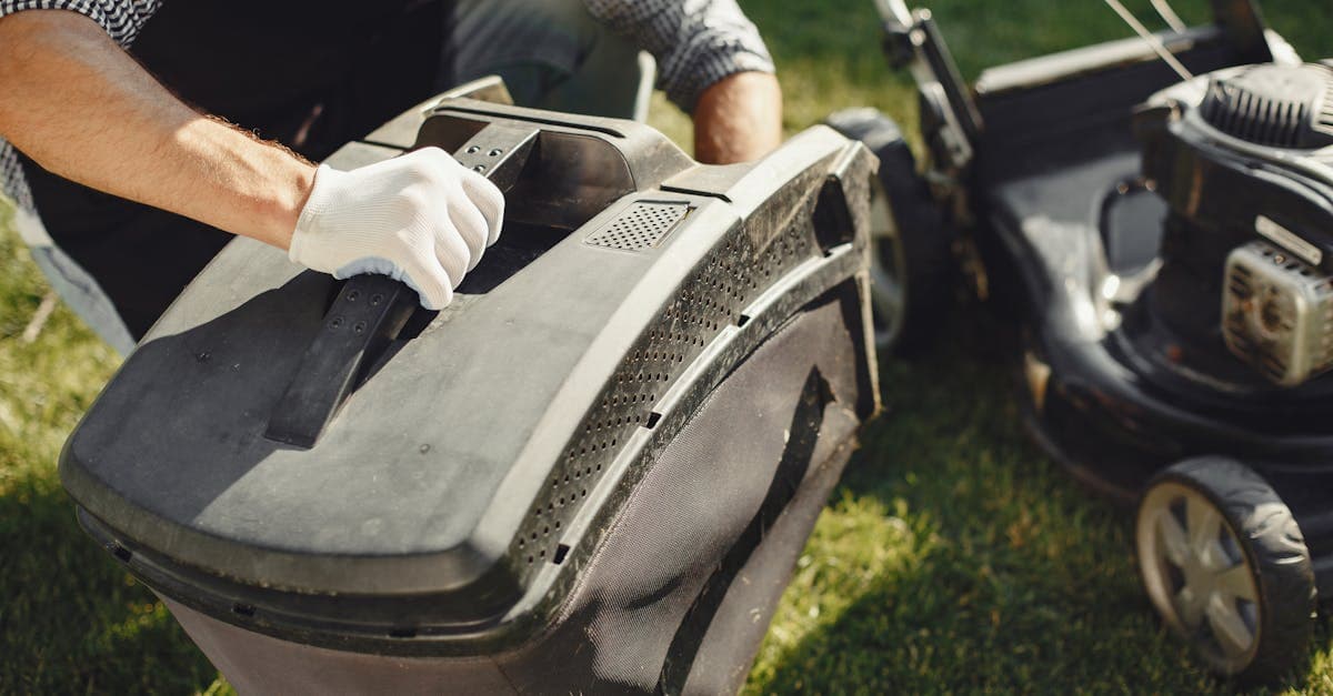 An adult man replacing a lawn mower bag on a sunny day in the yard.