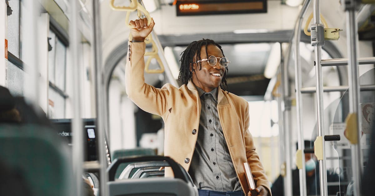 African American man standing and smiling inside a tram in an urban setting.