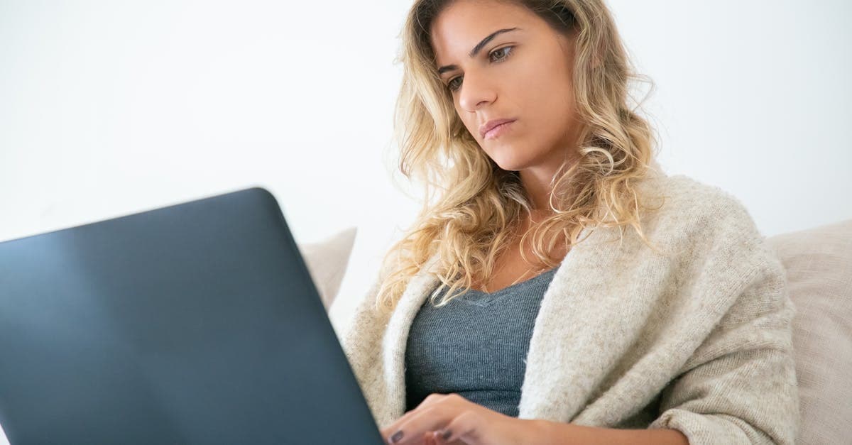 Blonde woman working on a laptop, deeply focused in a cozy home setting.