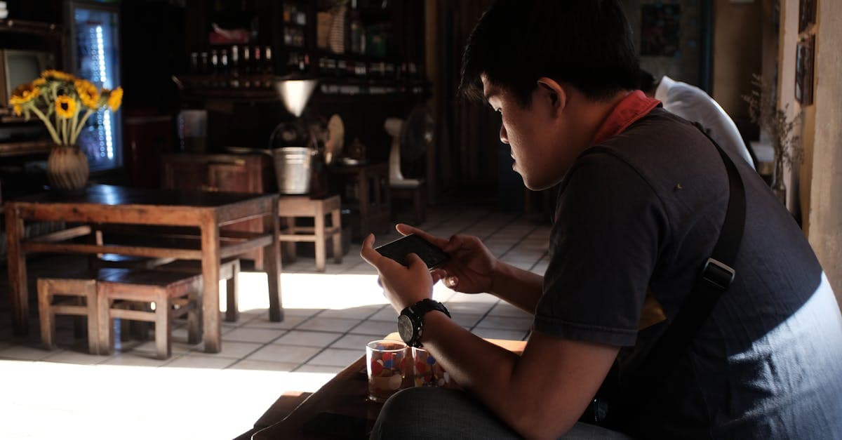 Man sitting indoors using smartphone in a rustic cafe, enjoying the tranquil atmosphere.