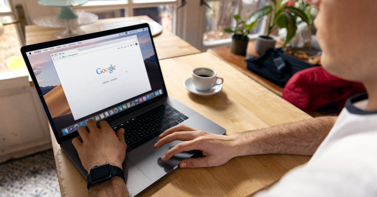 A person uses a laptop for internet browsing. A bright indoor setting with coffee on a wooden table.