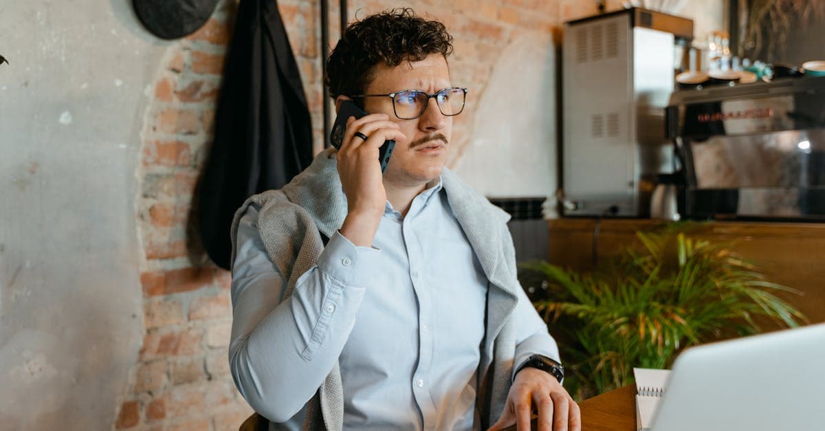 Man with glasses and mustache on a phone call in a cozy cafe.